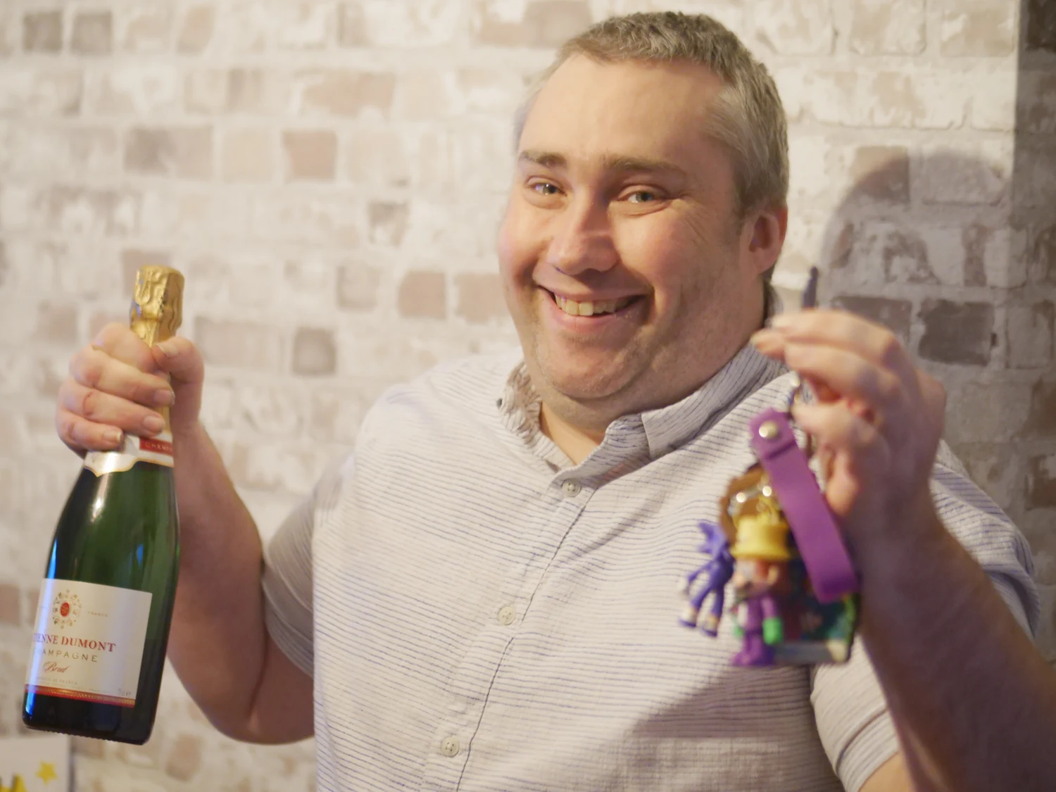 A man smiling as he celebrates with a bottle and gifts